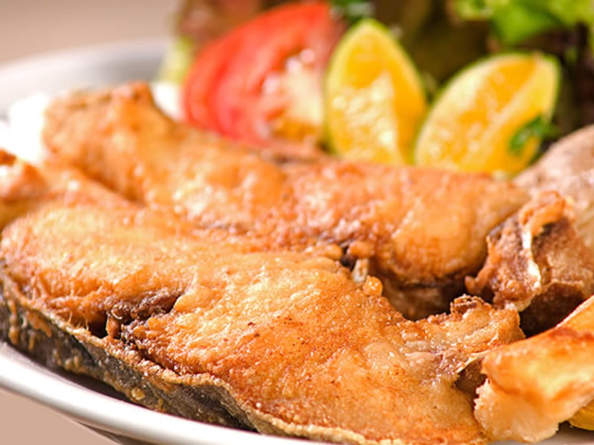 Rodaja de bagre frito y dorado, servida con tomate, limón y ensalada