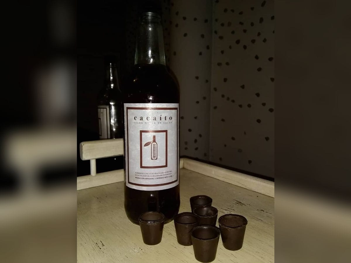 Botella de cacaíto, licor casero de cacao y ron, junto a copitas de chocolate