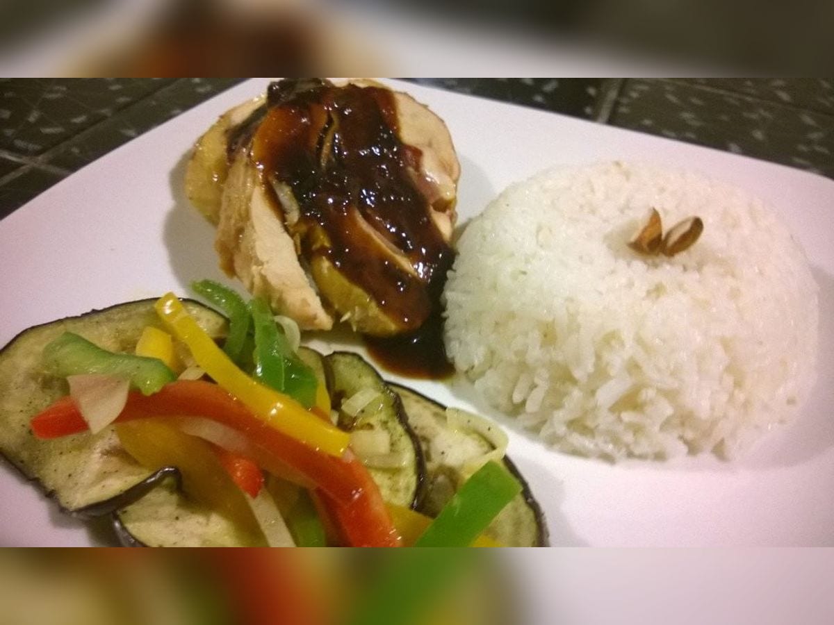 Ballotine de pollo en rodajas bañado en salsa oscura, servido con arroz blanco y berenjenas asadas