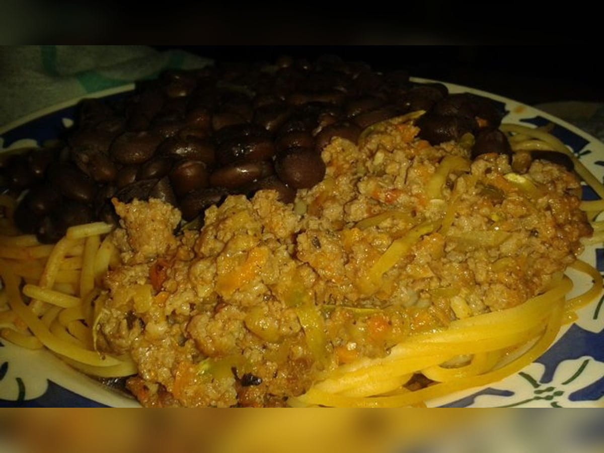 Plato con espagueti, caraotas negras y carne molida guisada servidos juntos