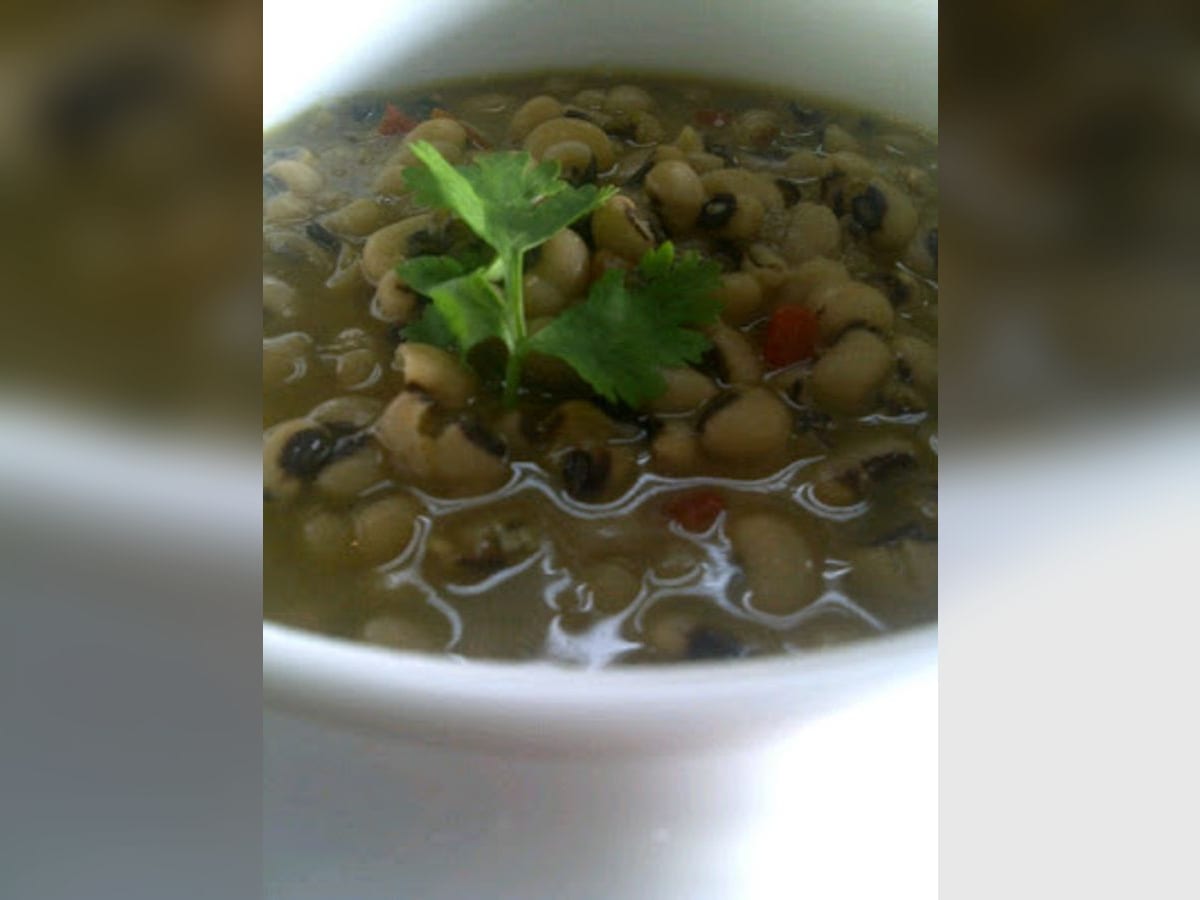 Frijoles en coco servidos en un tazón blanco, con cilantro fresco por encima