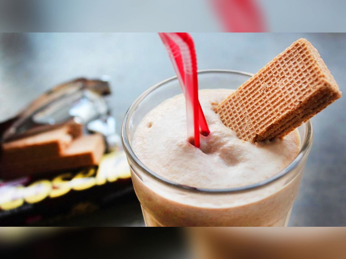 Merengada de cocosette servida en un vaso con una galleta de cocosette y un pitillo rojo