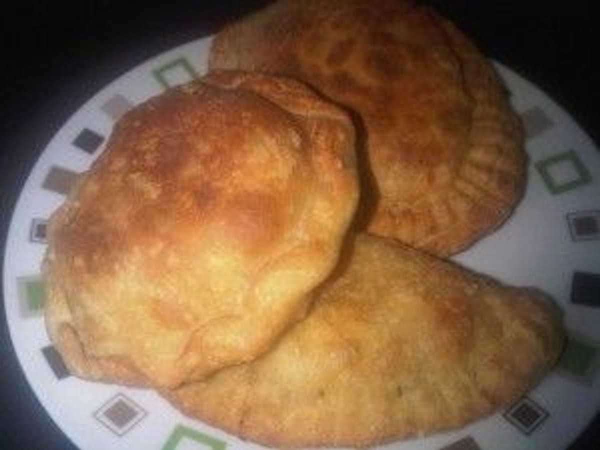 Pasteles andinos fritos, dorados y rellenos, apilados en un plato
