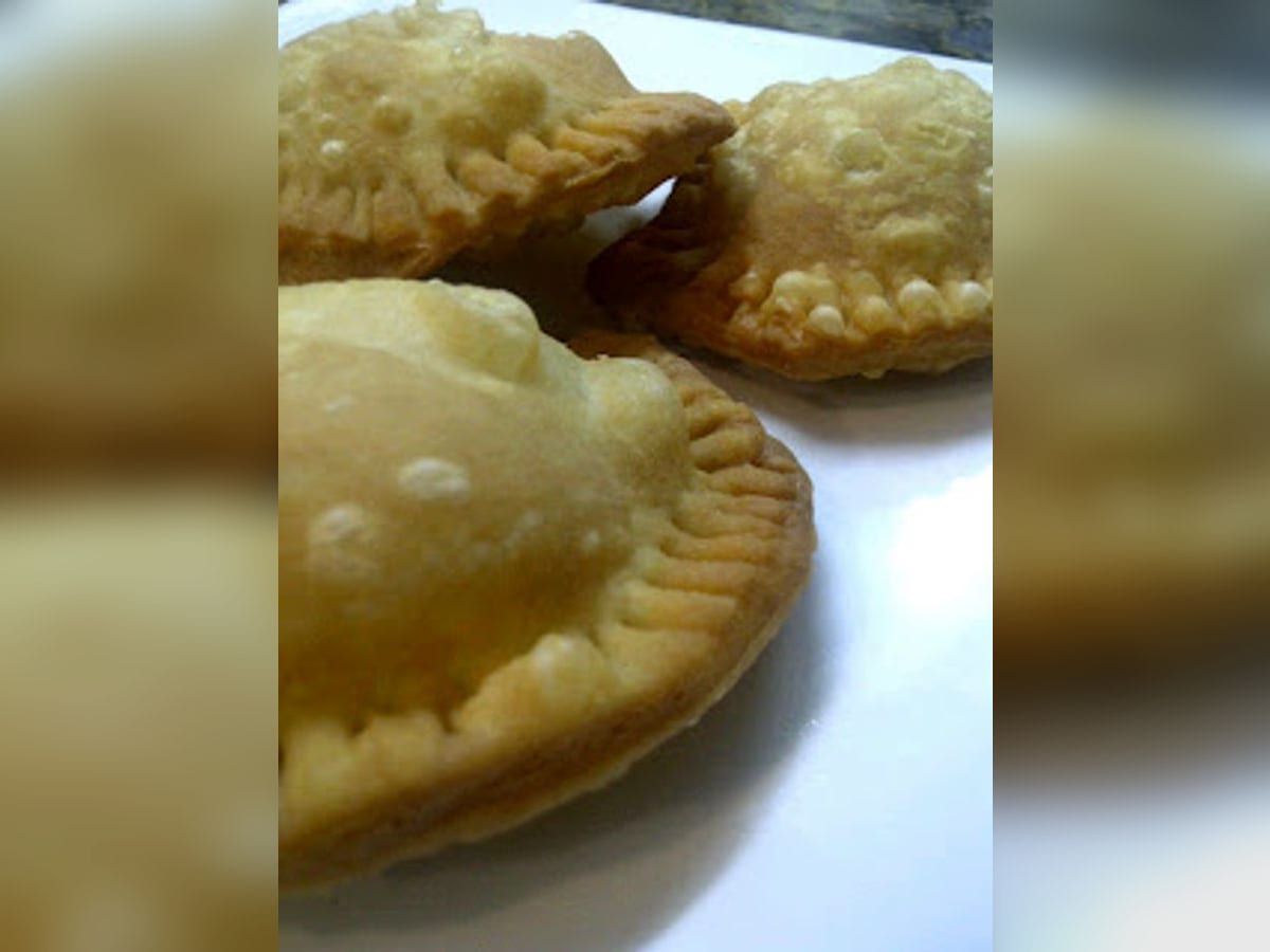 Pastelitos zulianos fritos y dorados, rellenos de papa y queso, servidos en un plato