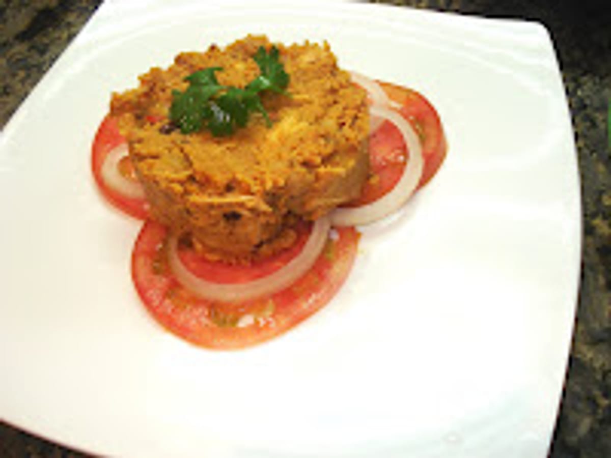 Revuelto de pollo moldeado, servido sobre ruedas de tomate y cebolla con cilantro