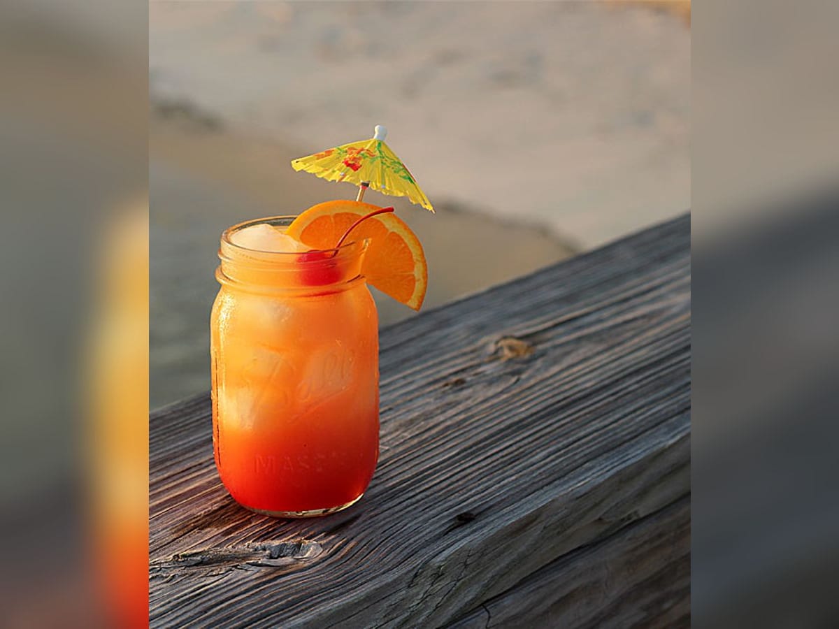 Rum punch servido en vaso bajo con hielo picado y decorado con naranja