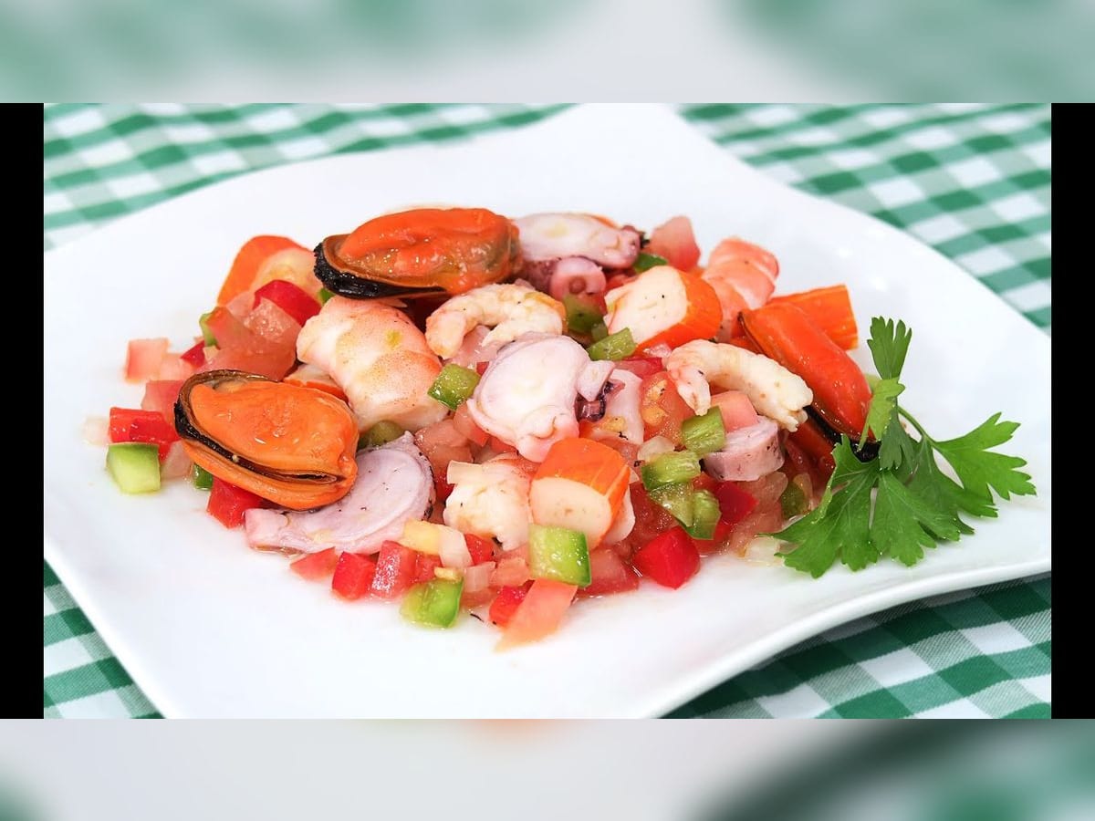 Salpicón de mariscos servido en un plato blanco, con langostinos, mejillones y vegetales picados